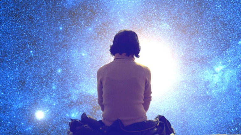 Woman sitting on jacket, looking at starry sky