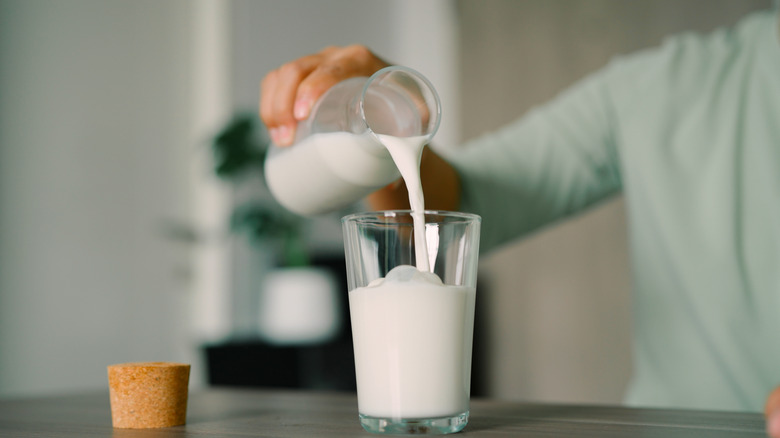Person pouring milk into a glass
