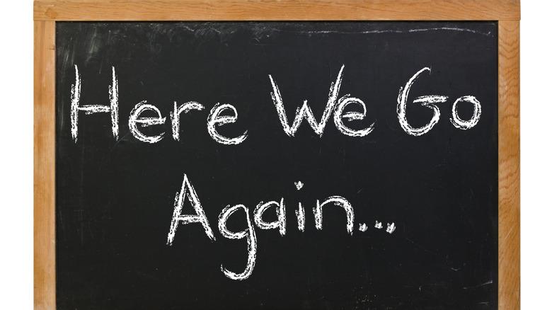 Blackboard with the words, "Here We Go Again" written on it