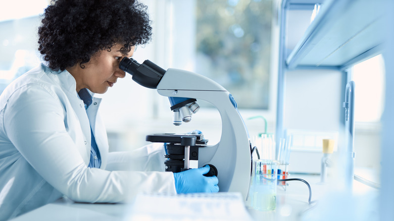 Woman in labcoat looking into a microscope