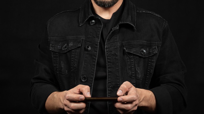 Man wearing black jacket and shirt while holding phone