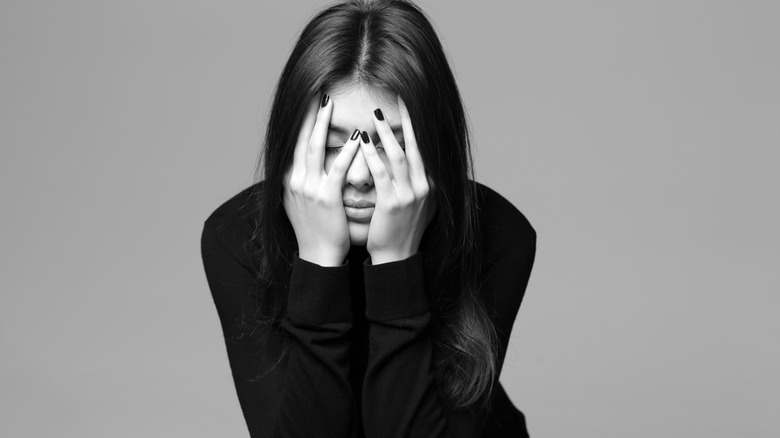 Woman wearing all black with head in hands