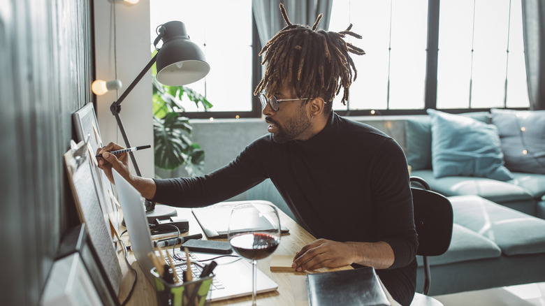 Man working on drawings on desk wearing black sweater