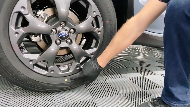 Mechanic pointing out the yellow dot on a tire while a red dot is also visible