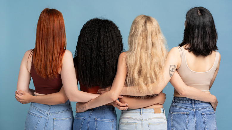 Four women with different hair types and colors facing away from the camera