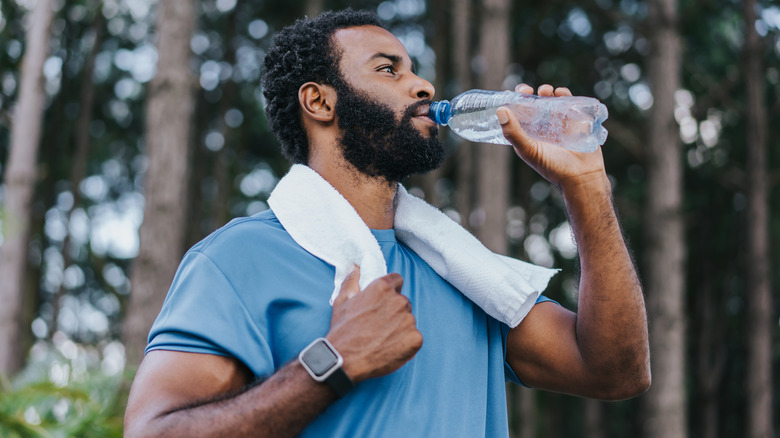 Man drinking a bottle of water outdoors