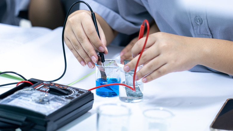 Chemist experiments with electrolyte solutions in beakers