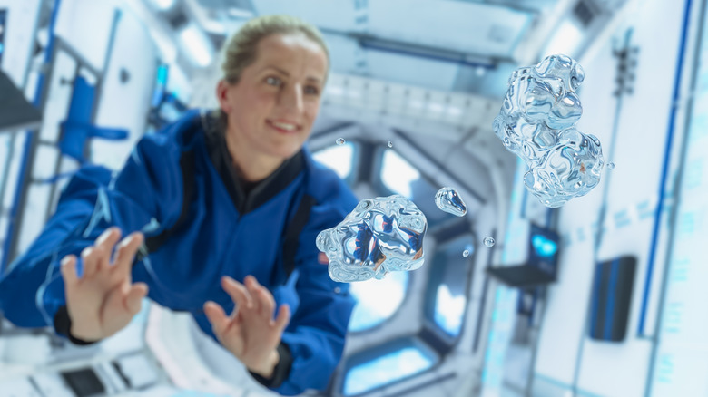 Astronaut in zero gravity with gobs of water floating around her head