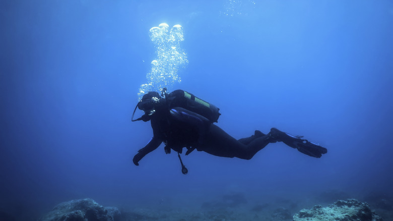 Scuba diver exploring rocks on the sea bed