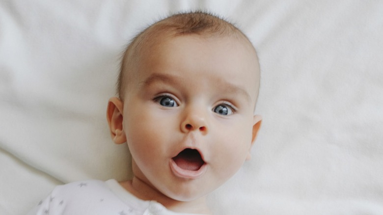 Baby with a surprised expression of wide eyes and open mouth