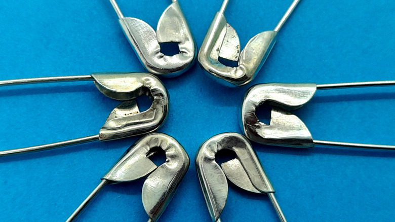 Close-up of the tops of safety pins in a circle facing each other