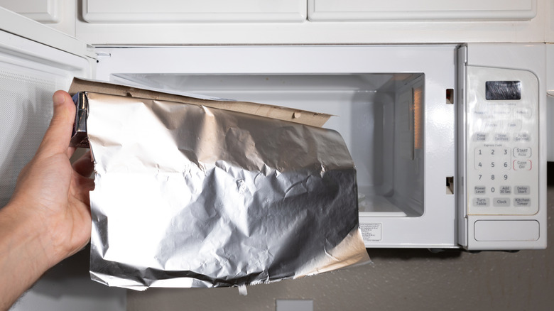 person putting aluminum foil into a mircowave