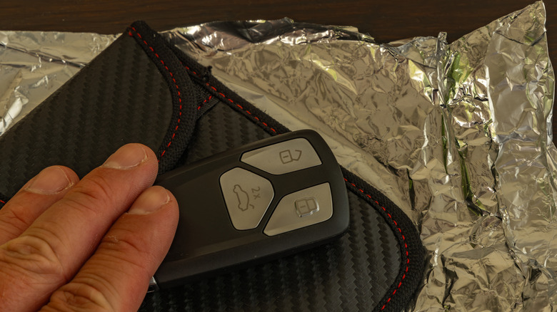 A hand wrapping a car key in aluminum foil