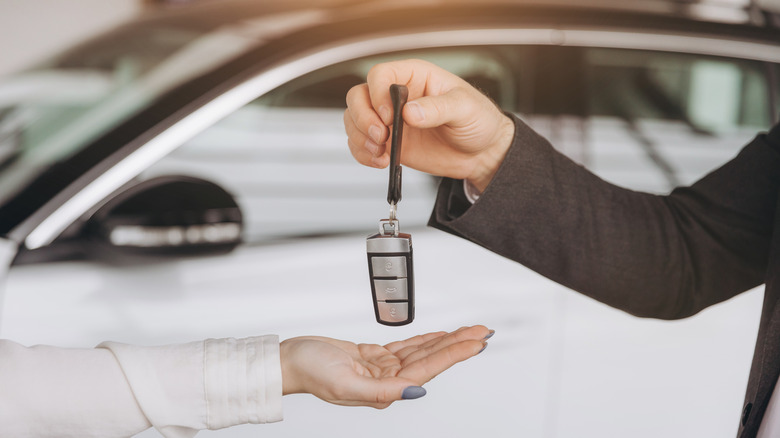 A man handing a car smart key to a woman