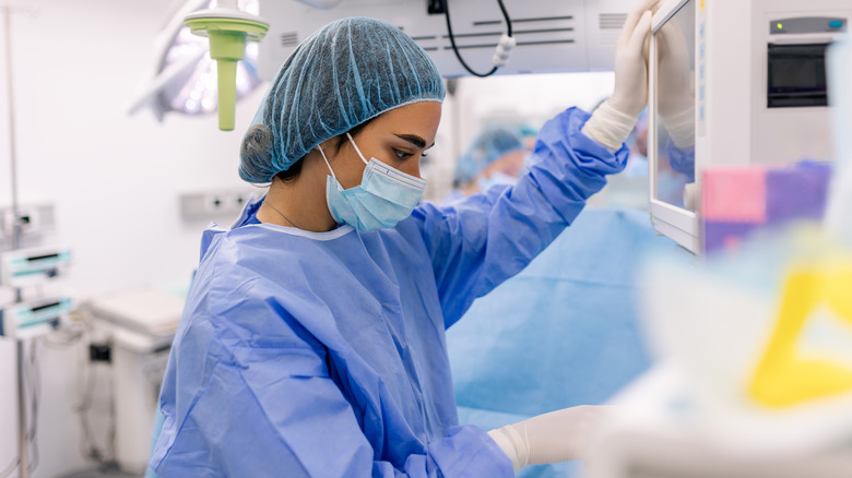 A surgeon wearing personal protective equipment, including a gown, gloves, hair net, and face mask.