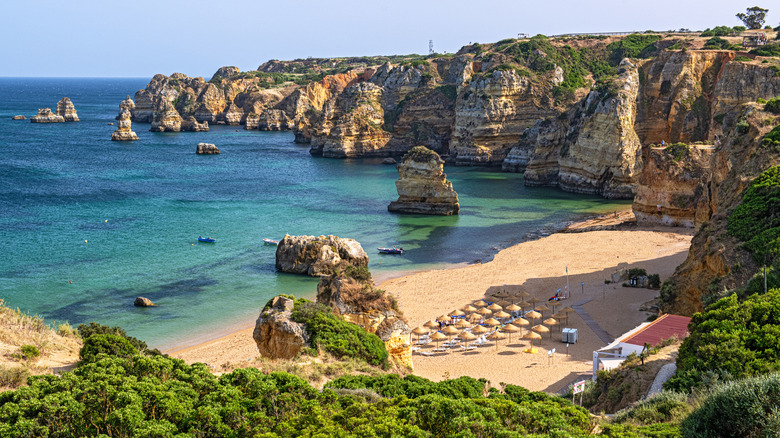 Beach with sand and cliffs overlooking blue water in Portugal