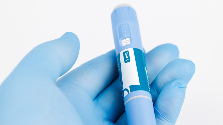 Semaglutide syringe held in blue-gloved hand
