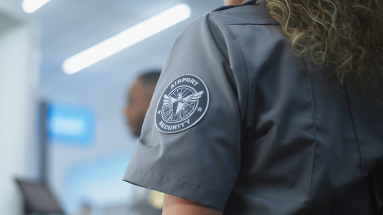 An airport security badge is seen on the arm of an officer's shirt