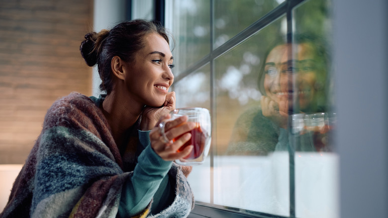 A woman in a blanket drinking tea