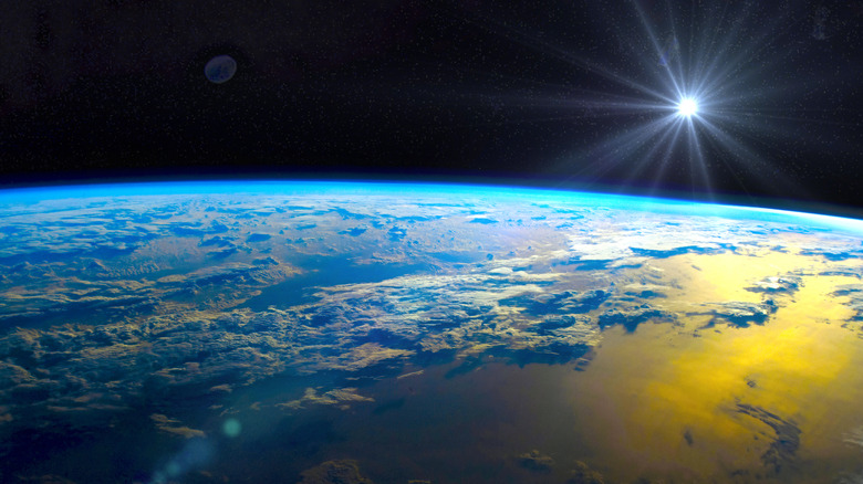 The surface of Earth seen from space with the sun in the distance