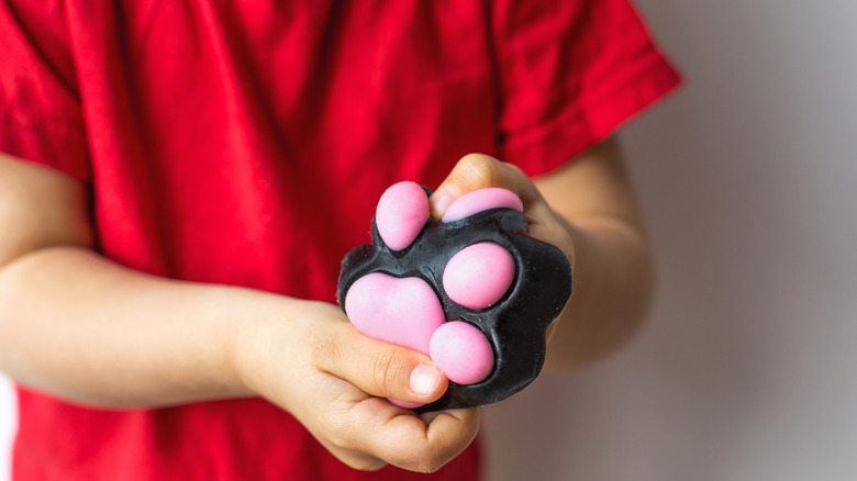 A child in a red shirt plays with a black and pink squishy toy