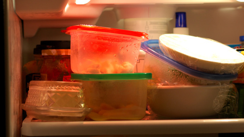 Plastic containers of leftovers stacked in a refrigerator