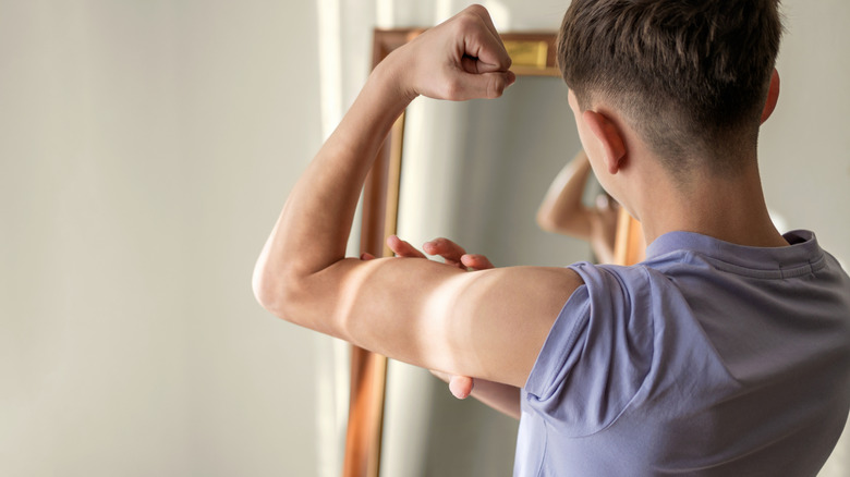 A man looks at his arm muscles in the mirror