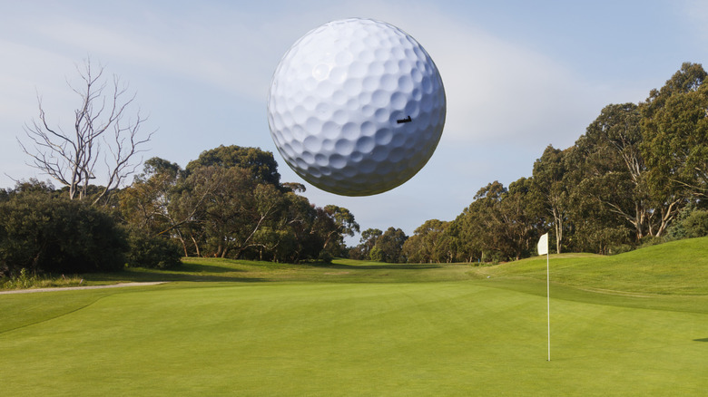 Golf ball flying in the air toward a pin and hole