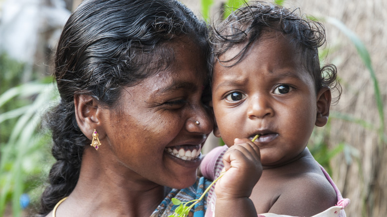 beautiful mother smiling pressing forehead against bright-eyed baby