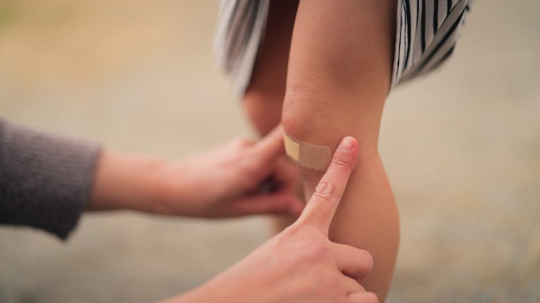 A person applying a bandaid to a knee