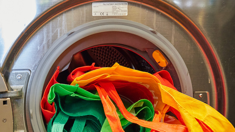 Multicolored reusable bags sticking out of a washing machine