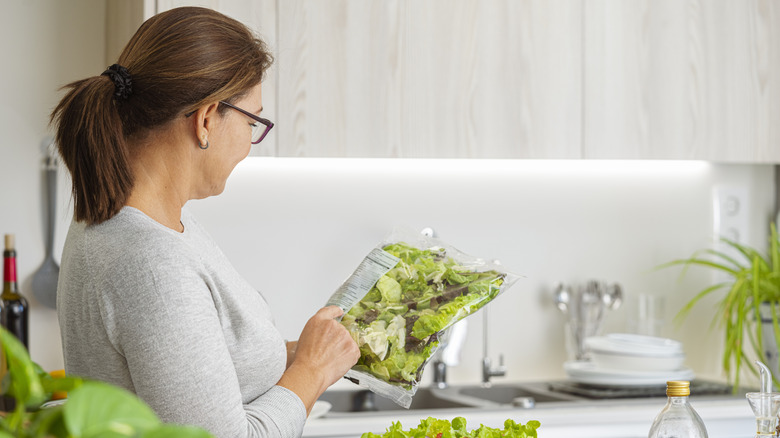 Woman reading the back label of a bagged lettuce product