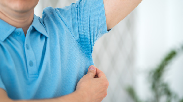 A man in a blue polo with sweaty armpits