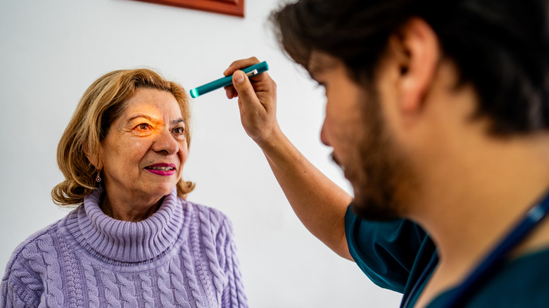 A doctor examining the eyes of a senior patient.