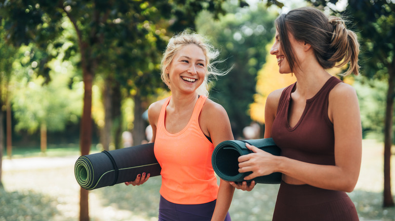 Two women carrying yoga mats