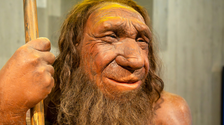 A bearded Neanderthal man is smiling