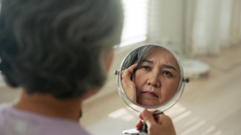 A woman looks at her reflection in a mirror