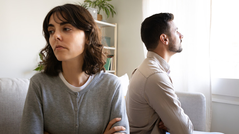 A man and woman couple with arms crossed, facing away from each other