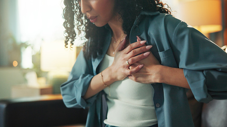 Woman holding hands over chest in pain