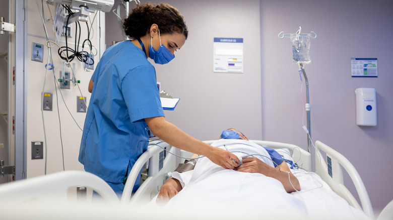 Nurse checking on a man in a hospital bed