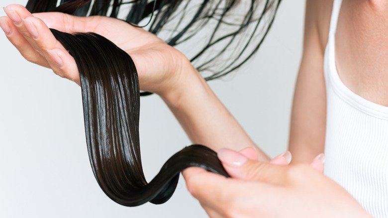 A close up of a woman holding a portion of her wet hair.