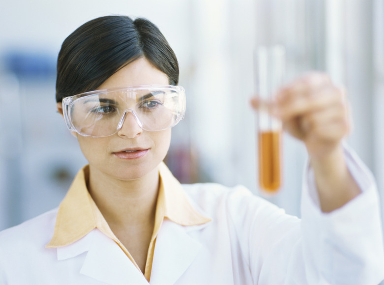Woman holding a test tube filled with orange liquid