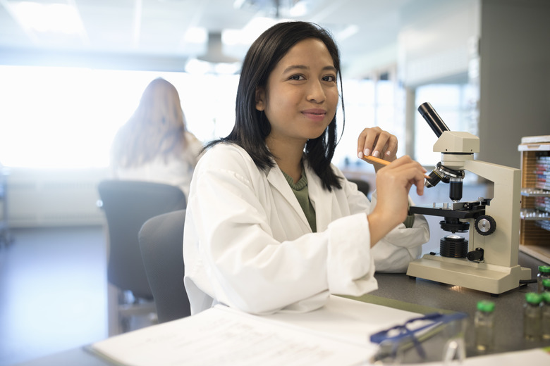Portrait smiling, confident female college student conducting scientific experiment at microscope
